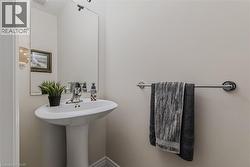 Pedestal sink with chrome faucet, large wall-mounted mirror, and a contemporary wall sconce providing illumination - 