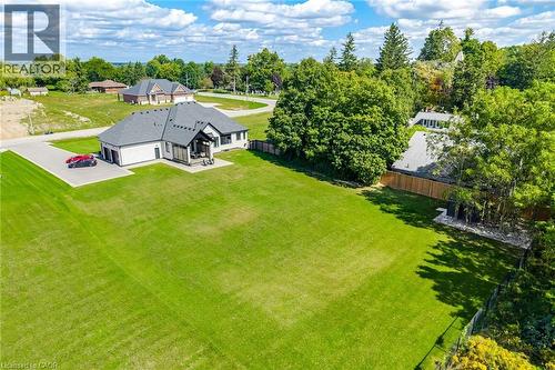 Expansive green lawn surrounding a residence with a dark shingle roof, light-colored siding, attached garage, and a paved driveway - 56 Augustus Street, Scotland, ON 