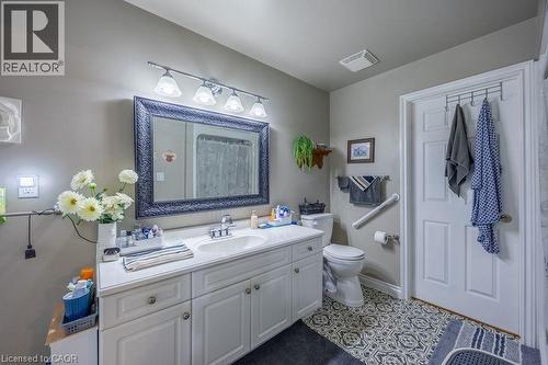 White vanity with a single basin sink, framed mirror, and decorative tile flooring - 123 Mill Street, Delhi, ON 