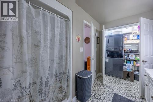 Built-in laundry closet with stacked washer and dryer, patterned floor tile, and white cabinetry with drawer pulls - 123 Mill Street, Delhi, ON 