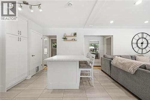 White shaker-style cabinetry with silver hardware, recessed lighting, track lighting, light-toned tile flooring, and a stone-finish island countertop - 312 Upper Paradise Road, Hamilton, ON 