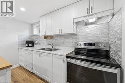 White shaker cabinetry with brushed nickel hardware, stainless steel appliances, light-toned countertop, mosaic tile backsplash, and wood-finish flooring - 