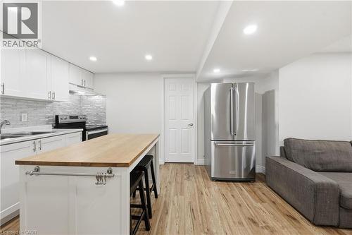 Full kitchen with white cabinetry, stainless steel appliances, wood-finish flooring, and recessed lighting - 312 Upper Paradise Road, Hamilton, ON 