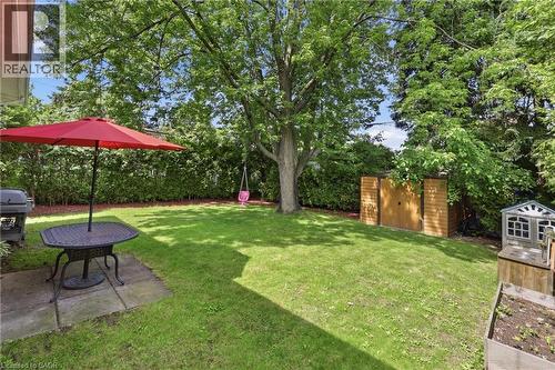 Expansive backyard featuring a lush lawn, mature trees, concrete patio, and privacy hedging - 312 Upper Paradise Road, Hamilton, ON 