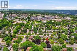 Suburban neighborhood with mature trees, established residential properties, and distant commercial structures - 