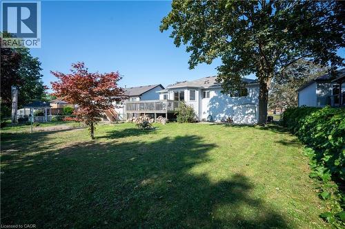 Expansive backyard featuring a large elevated wood deck, mature trees, and a manicured lawn - 12 Langevin Drive, Wasaga Beach, ON 