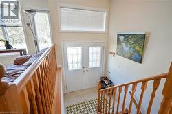 Double entry doors with decorative glass panels, transom window, tile flooring, and wood stair railing - 