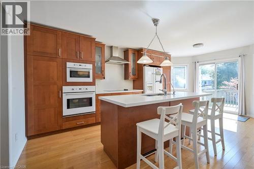 Hardwood flooring throughout, built-in ovens, wood cabinetry, center island with sink, and sliding glass door with exterior deck - 12 Langevin Drive, Wasaga Beach, ON 
