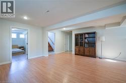 Recessed lighting, wood-finish flooring, light-toned walls, and a wood staircase with handrail - 