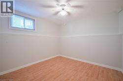 Wood-finish flooring, white walls with chair rail molding, ceiling fan with integrated lighting, and a white-framed window with blinds - 