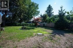 Expansive backyard featuring mature trees, established greenery, and a wood privacy fence - 