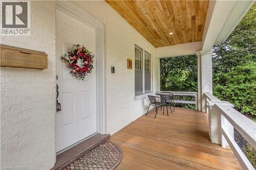 Covered porch featuring wood-finish flooring, a white paneled door, and a natural wood ceiling with recessed lighting - 11 Tutela Heights Road, Brantford, ON 