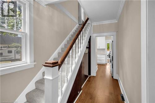 Hardwood flooring, carpeted staircase, white newel post with wood-finish cap, white window trim, and crown molding - 11 Tutela Heights Road, Brantford, ON 
