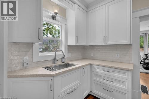 White cabinetry, light-toned countertops, subway tile backsplash, stainless steel sink, and a modern pull-down faucet - 11 Tutela Heights Road, Brantford, ON 