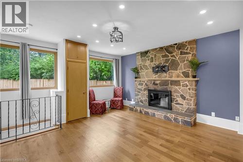 Stone fireplace with a hearth, wood-finish flooring, built-in cabinetry, recessed lighting, and a decorative ceiling fixture - 11 Tutela Heights Road, Brantford, ON 