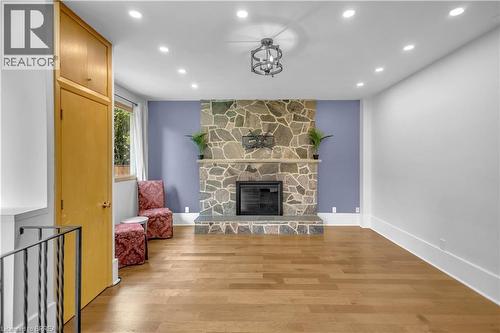 Hardwood flooring, recessed lighting, stone fireplace, modern chandelier, and built-in cabinetry - 11 Tutela Heights Road, Brantford, ON 