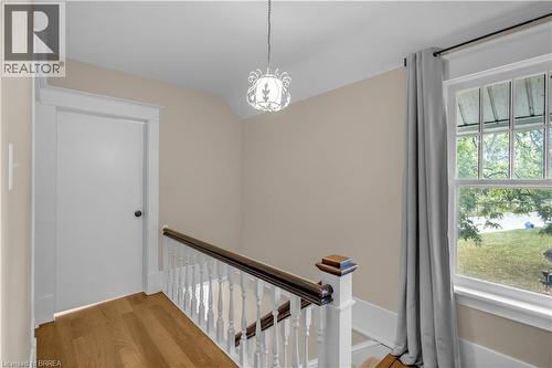 Hardwood-finish flooring, white spindle banister with wood-finish railing, single-hung window, and decorative ceiling light fixture - 11 Tutela Heights Road, Brantford, ON 