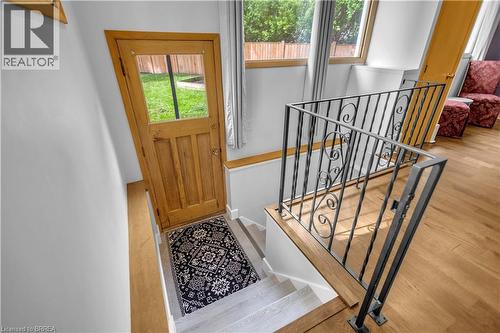 Hardwood flooring, painted white walls, wood-framed door with glass panel, wrought iron railing with scrollwork, and a wooden handrail - 11 Tutela Heights Road, Brantford, ON 