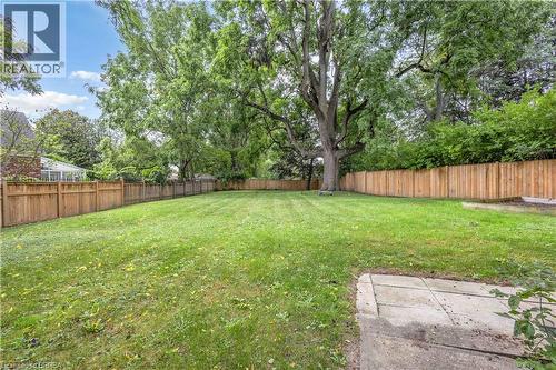 Expansive backyard featuring a manicured lawn, mature trees, and privacy fencing - 11 Tutela Heights Road, Brantford, ON 