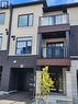 Contemporary facade with mixed material finishes, featuring a full-light entry door, integrated garage, and two upper-level balconies with glass railings - 155 Equestrian Way Unit# 152, Cambridge, ON 