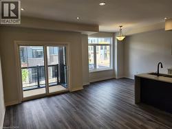 Spacious living area featuring wood-finish flooring, recessed lighting, and a sliding glass door opening to a private balcony with black metal railings - 