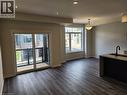 Spacious living area featuring wood-finish flooring, recessed lighting, and a sliding glass door opening to a private balcony with black metal railings - 155 Equestrian Way Unit# 152, Cambridge, ON 