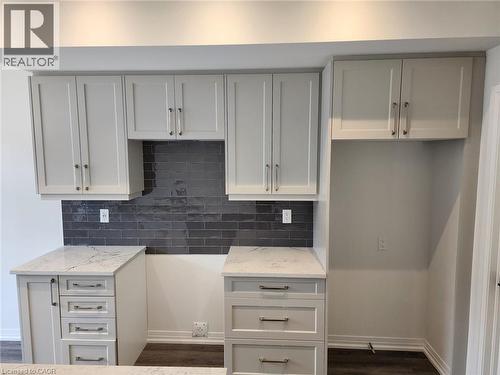 White shaker-style cabinetry, white countertops with subtle veining, dark subway tile backsplash, and dark wood-finish flooring - 155 Equestrian Way Unit# 152, Cambridge, ON 