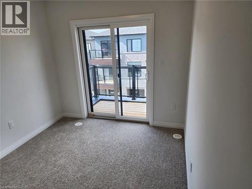 Sliding glass door leading to an outdoor balcony with wood-finish decking and black railings - 155 Equestrian Way Unit# 152, Cambridge, ON 