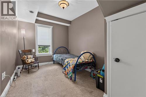 Carpeted room featuring a single window with blinds, a ceiling-mounted light fixture, crown molding, and a white interior door with black hardware - 42841 Highway 3, Wainfleet, ON 