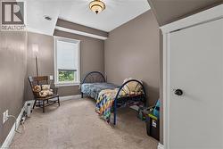Carpeted room featuring a single window with blinds, a ceiling-mounted light fixture, crown molding, and a white interior door with black hardware - 