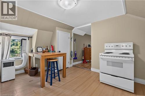 Kitchen area featuring a white electric range, light wood-finish flooring, and a window with exterior views - 42841 Highway 3, Wainfleet, ON 