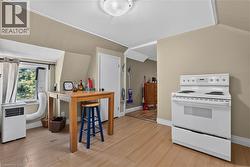 Kitchen area featuring a white electric range, light wood-finish flooring, and a window with exterior views - 