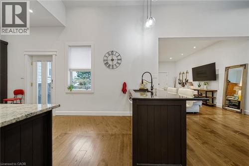 Hardwood flooring throughout, a kitchen island with a dark countertop and a gooseneck faucet, a white double-paned door, and a large window - 28 Cambridge Street, Cambridge, ON 