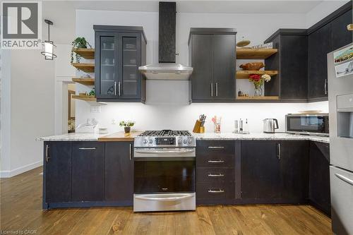 Modern kitchen featuring stainless steel appliances, dark wood-finish cabinetry, light-colored countertops, open shelving, and wood-finish flooring - 28 Cambridge Street, Cambridge, ON 
