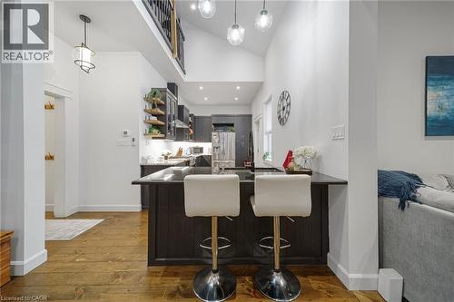 Vaulted ceiling with pendant lighting, wood-finish flooring, dark wood cabinetry, built-in shelving, and a kitchen island with counter seating - 28 Cambridge Street, Cambridge, ON 