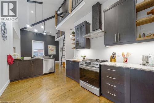 Vaulted ceilings with exposed beams, wood-finish flooring, stainless steel appliances, dark wood-finish cabinetry, and light-toned countertops - 28 Cambridge Street, Cambridge, ON 
