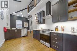 Vaulted ceilings with exposed beams, wood-finish flooring, stainless steel appliances, dark wood-finish cabinetry, and light-toned countertops - 