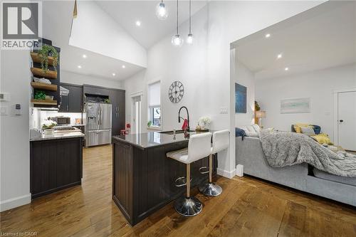 Kitchen with wood-finish flooring, dark cabinetry, recessed lighting, and a kitchen island with seating - 28 Cambridge Street, Cambridge, ON 