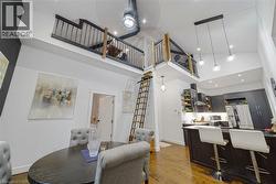 Vaulted ceilings, wood-finish flooring, and a contemporary kitchen with dark cabinetry and stainless steel appliances - 