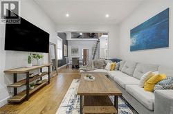 Open-concept living space with wood-finish flooring, recessed lighting, and a partial second-story overlook - 