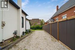 Gravel driveway with a corrugated metal fence, complemented by a brick-clad building - 