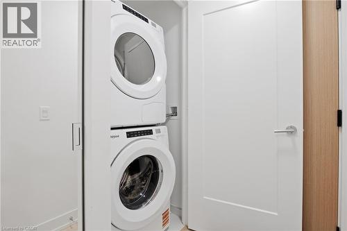 Stacked washer and dryer unit, white flat panel door with brushed nickel hardware, and wood-finish door casing - 60 Central Park Roadway Unit# 2010, Etobicoke, ON 