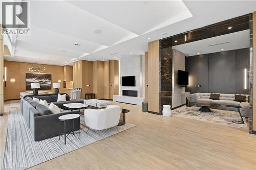 Spacious common area featuring wood-finish flooring, recessed lighting, a built-in electric fireplace, and dark stone accent walls - 60 Central Park Roadway Unit# 2010, Etobicoke, ON 