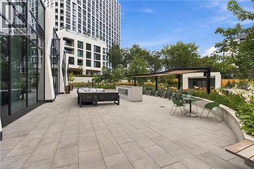 Expansive outdoor patio with large format pavers and curved planter beds, featuring an integrated pergola and modern exterior lighting - 60 Central Park Roadway Unit# 2010, Etobicoke, ON 
