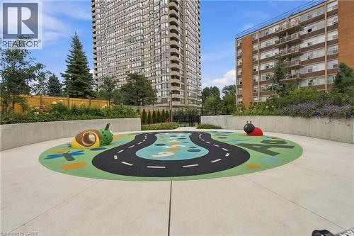 Outdoor play area with a colorful soft-surface design, raised concrete planters, and perimeter fencing - 60 Central Park Roadway Unit# 2010, Etobicoke, ON 