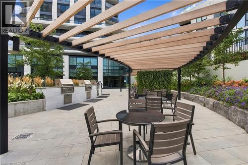 Spacious patio area featuring a slatted wood pergola, built-in outdoor grills, and stone paver flooring - 60 Central Park Roadway Unit# 2010, Etobicoke, ON 