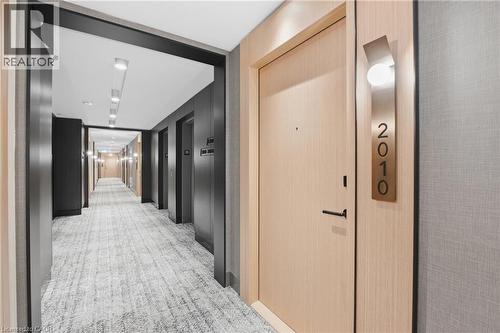 Corridor featuring light wood-finish doors, modern metallic address signage, recessed ceiling lighting, and textured wall coverings - 60 Central Park Roadway Unit# 2010, Etobicoke, ON 