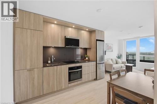 Integrated kitchen featuring wood-finish cabinetry, stainless steel appliances, and dark countertops - 60 Central Park Roadway Unit# 2010, Etobicoke, ON 