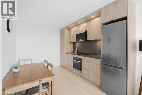 Compact kitchen featuring wood-finish cabinetry, stainless steel appliances, recessed lighting, and light wood-finish flooring - 60 Central Park Roadway Unit# 2010, Etobicoke, ON 