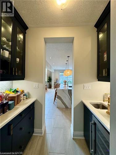 Built-in cabinetry with glass display doors, white countertops, stainless steel sink, and wood-finish flooring - 923 Eaglecrest Court, Kitchener, ON 